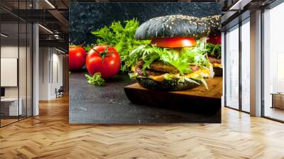 Freshly homemade black burgers with cheese, beef minced steak, tomato and lettuce. On the black concrete background, copy space Wall mural