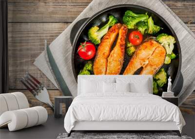 Healthy eating, diet. Baked grilled trout (salmon) with vegetable garnish - broccoli, tomatoes. In a portioned frying pan, on a wooden table. Top view copy space Wall mural