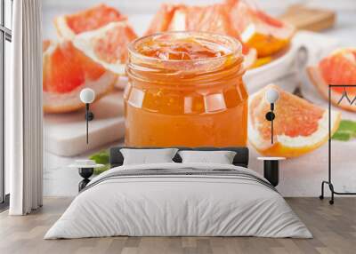 Homemade grapefruit jam, sweet pink grapefruit marmalade in small jar, with grapefruit slices and mint leaves on white table background Wall mural