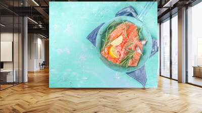 Salmon. Fresh raw salmon fish fillet with cooking ingredients, herbs and lemon in cooking pan, skillet, light blue Turquoise background, top view Wall mural