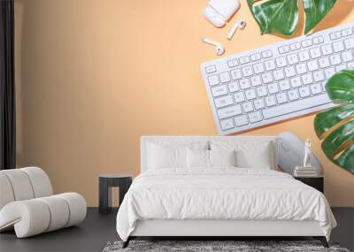 Summer office background with keyboard. Simple minimal beige flatlay with tropical monstera leaf, white keyboard, mouse, earphones, top view copy space Wall mural