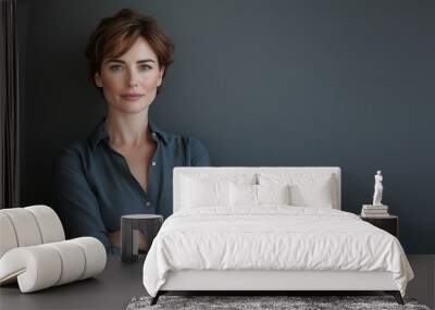 A confident businesswoman stands with her arms crossed against a dark gray background, looking directly at the camera in front of an empty space for copy text or product display Wall mural