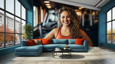 short woman with curly brunette hair smiling in gym portrait Wall mural