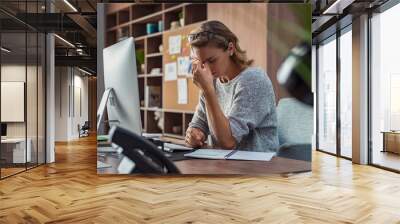 Business woman having headache at office Wall mural