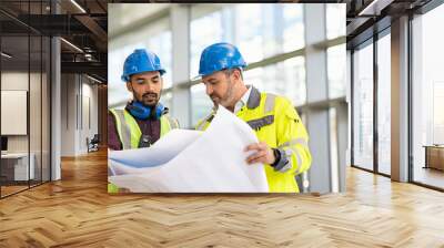 Construction site worker and engineer discussing on blueprint project Wall mural