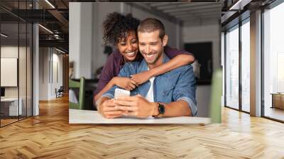 Happy couple looking at phone together Wall mural