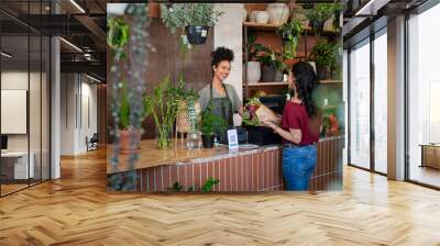 Happy florist selling plants and flower to client Wall mural