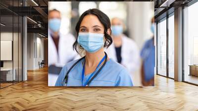 Happy nurse with face mask smiling at hospital Wall mural