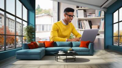 Happy young businessman working on laptop Wall mural