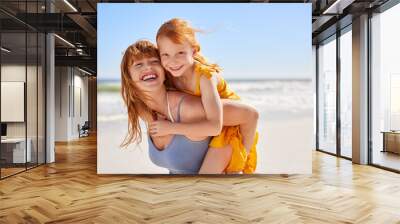 Happy young mother giving daughter a piggyback ride at beach Wall mural