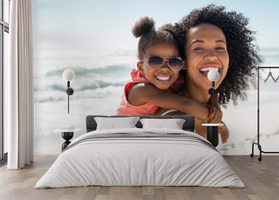 Happy young mother giving laughing daughter piggyback ride at beach Wall mural