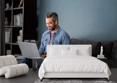 Indian man typing on laptop while working from home Wall mural