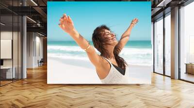 Latin carefree woman with outstretched arms at beach Wall mural