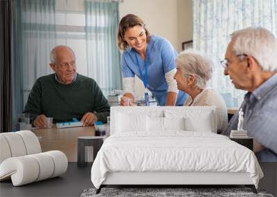 Lovely nurse giving medicine to senior woman at care facility Wall mural