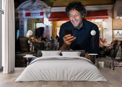 Mature happy man using phone at night Wall mural