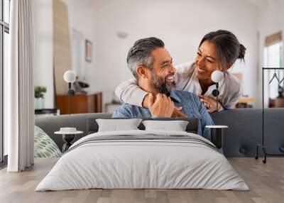 Mature multiethnic couple laughing and embracing at home Wall mural