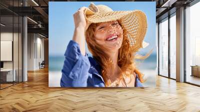 Portrait of happy smiling woman at beach wearing straw hat Wall mural