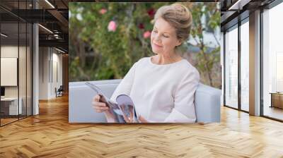 Senior woman reading magazine Wall mural