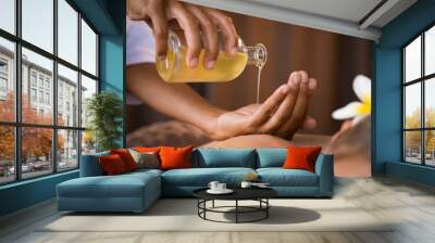 Therapist pouring massage oil at spa Wall mural