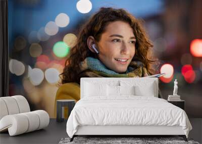 Woman sending voice note on city street in winter night Wall mural