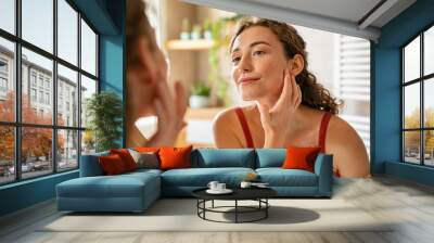 Young beauty woman checking her skin at mirror in the morning Wall mural