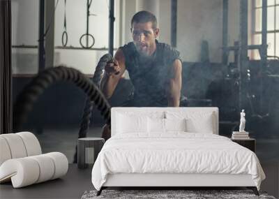 Young man exercising using battle rope Wall mural