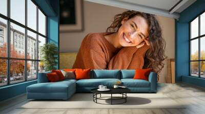 Young woman laughing while relaxing at home Wall mural