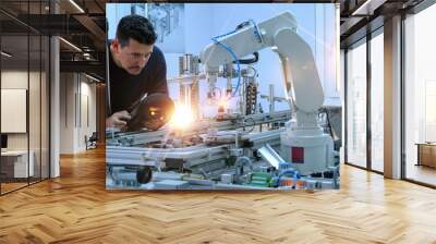 Man is programming robotic arm with control panel which is integrated on smart factory production line. industry 4.0 automation line which is equipped with sensors and robotic arm. Selective Focus. Wall mural