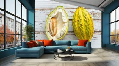 Half sliced ripe yellow cacao pod with white cocoa seed ,Cut in half fresh ripe cacao and green raw cacao fruit on white wooden background Wall mural