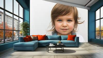 Beautiful blonde Caucasian toddler child with blue eyes closeup portrait. Calm and serious attentive girl on isolated background Wall mural