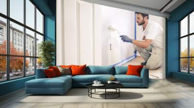 Painter man painting the wall in home, with paint roller and white color paint. Wall mural