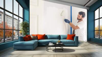 Painter man painting the wall in home, with paint roller and white color paint. Wall mural