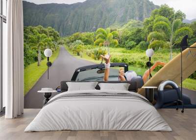 Road trip travel - girls driving car in freedom. Happy young girls cheering in convertible car on summer Hawaii vacations. Wall mural