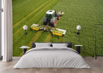 Aerial view of a tractor mowing a green fresh grass field, 
a farmer in a modern tractor mowing a green fresh grass field on a sunny day Wall mural