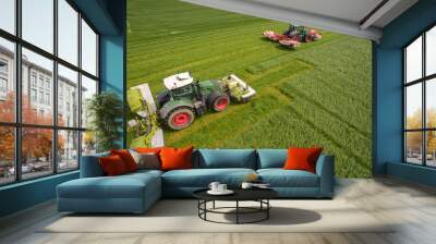 Aerial view of two tractor mowing a green fresh grass field, 
 farmer in a modern tractors mowing a green fresh grass field on a sunny day Wall mural