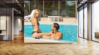 Attractive young couple relaxing in the hotel swimming pool Wall mural