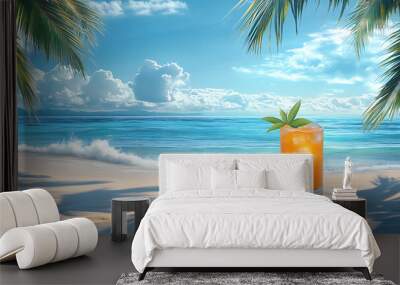 A tall orange drink on a sandy beach with palm trees and a blue ocean. Wall mural