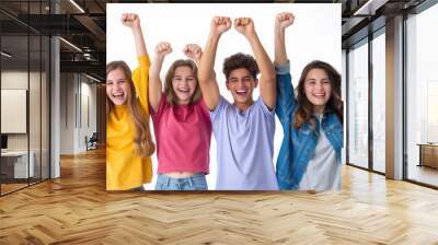 Group of four teenagers raising their arms in excitement, wearing colorful casual clothes, against a white background. Wall mural