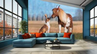 Pony and dog with bunny ears on their heads. Funny Easter bunnies. Wall mural