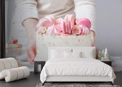 Confectioner puts a beautiful white cake with macarons and roses on a table Wall mural