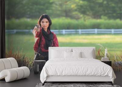 A beautiful western cowgirl sits on a fence and points to a self defense gun while working on the farm Wall mural