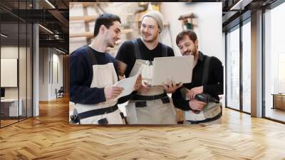 Master of small business with laptop and his team as sign of innovation in carpenter workshop. startup business, young specialist Wall mural