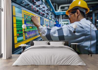 An engineer in a hard hat and safety goggles operating a control panel in an industrial setting, representing technology, industry, and safety. Wall mural