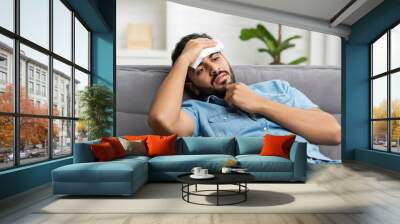 Man Holding Cold Compress To Forehead On Sofa Wall mural