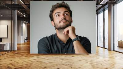 Portrait of a thoughtful man looking up with hand on chin Wall mural