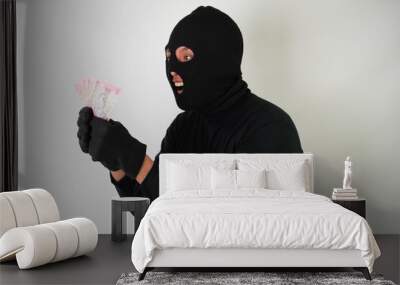 Dangerous young Adult black masked robber is holding a bunch of indonesian money after stealing from his victim. Wall mural