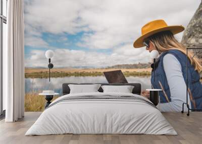 A woman is sitting on the grass with a laptop in front of her. Huayllay Stone Forest, Peru. Remote work concept Wall mural