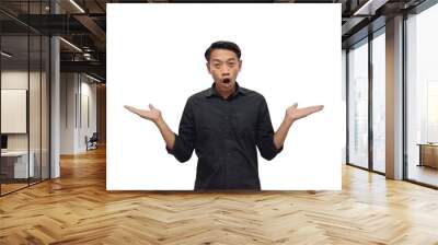 Overjoyed young Asian man in casual black shirt looking aside and showing copy space on palm isolated on white background. Great offer concept Wall mural