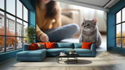 Beautiful young woman playing with cat on floor at home. Wall mural