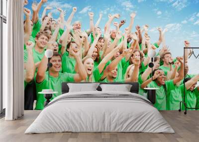 Crowd in green t-shirts cheering with arms raised Wall mural